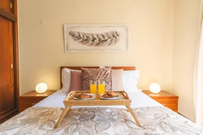 a bedroom with a bed with a tray of food on it at Strelitzia Apartment by AH in Caniço
