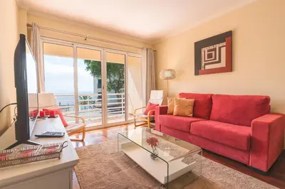 a living room with a red couch and a window at Strelitzia Apartment by AH in Caniço