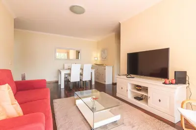 a living room with a red couch and a flat screen tv at Strelitzia Apartment by AH in Caniço