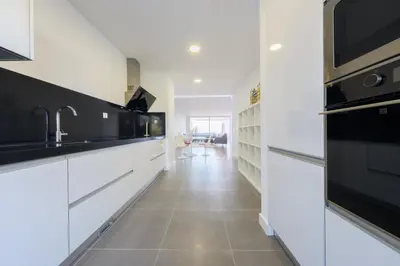 a kitchen with white cabinets and black appliances at Beach Condominium 27 by Destination Algarve in Santo Amaro