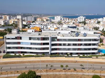 a large white building with a city in the background at Beach Condominium 27 by Destination Algarve in Santo Amaro