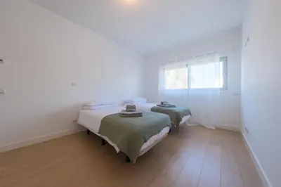 two beds in a white room with a window at Beach Condominium 27 by Destination Algarve in Santo Amaro