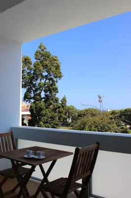 a wooden table and chairs on a balcony with a window at Mel Apartment in Funchal