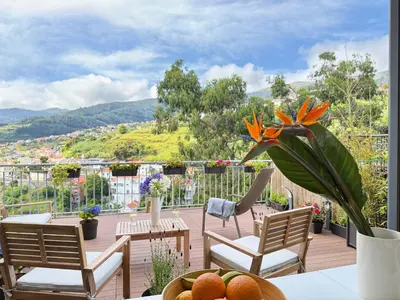 a balcony with chairs and a table with a flower at 10 min to Calheta Beach - Apartamento Da Natureza - KING Size Bed - LARGE Terrace in Arco da Calheta