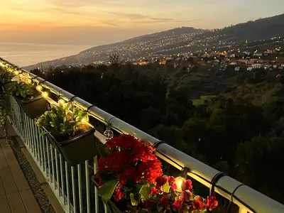 a balcony with flowers and lights on a mountain at 10 min to Calheta Beach - Apartamento Da Natureza - KING Size Bed - LARGE Terrace in Arco da Calheta