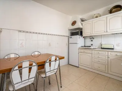 a kitchen with white cabinets and a wooden table and chairs at Traditional house by the beach #1979 in Luz