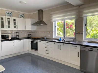 a large kitchen with white cabinets and windows at A casa da Xã in Almagreira