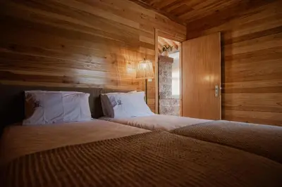 a bedroom with two beds with wooden walls at AZORINSITU - Casas da Ribeira in Vila do Porto
