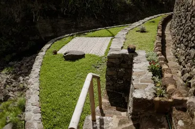 a stone retaining wall with a path and grass at AZORINSITU - Casas da Ribeira in Vila do Porto