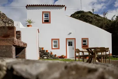 a white house with a table and chairs in front of it at AZORINSITU - Casas da Ribeira in Vila do Porto
