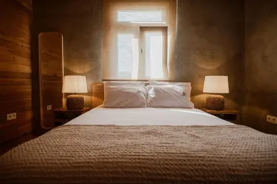 a bedroom with a large bed with two lamps at AZORINSITU - Casas da Ribeira in Vila do Porto
