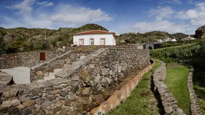 a stone wall with a house on top of it at AZORINSITU - Casas da Ribeira in Vila do Porto