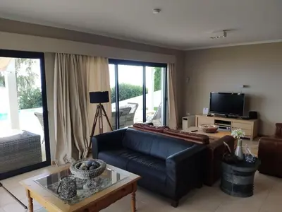 a living room with a couch and a tv at Villa 17°West with Pool in Estreito da Calheta