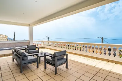 a balcony with chairs and a table and a view of the ocean at Quinta dos Louros in Estreito da Calheta
