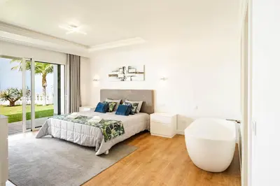 a white bedroom with a bed and a large window at Quinta dos Louros in Estreito da Calheta