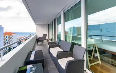 a balcony with chairs and a table and the ocean at Alameda in Funchal