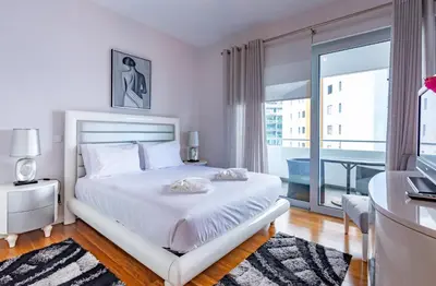 a white bedroom with a bed and a balcony at Alameda in Funchal