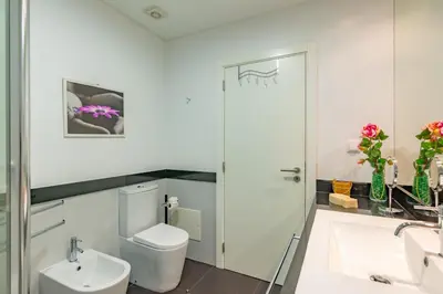 a white bathroom with a toilet and a sink at Alameda in Funchal