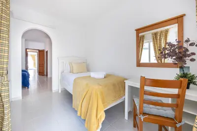 a bedroom with a bed and a chair and a mirror at Casa da Praia da Luz T2 plus 1 in Luz