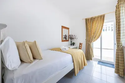 a white bedroom with a bed and a window at Casa da Praia da Luz T2 plus 1 in Luz