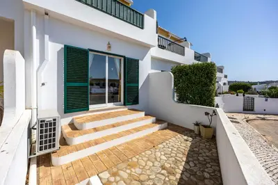 a white house with green shutters and stairs at Casa da Praia da Luz T2 plus 1 in Luz