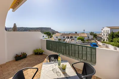 a balcony with tables and chairs and a view of the ocean at Casa da Praia da Luz T2 plus 1 in Luz