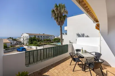 a balcony with a table and chairs and a palm tree at Casa da Praia da Luz T2 plus 1 in Luz
