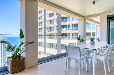 a balcony with a white table and chairs and a building at Funchal Acqua Blue 5L, a Home in Madeira in Funchal