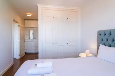 a bedroom with a white bed with a blue headboard at GuestReady - Caniço city view in Caniço