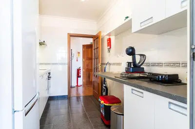 a kitchen with white cabinets and a counter top at GuestReady - Caniço city view in Caniço