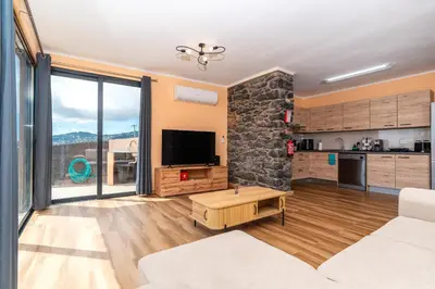 a living room with a tv and a stone wall at Casa Por Do Sol ll in Arco da Calheta