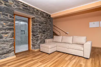 a living room with a couch and a stone wall at Casa Por Do Sol ll in Arco da Calheta