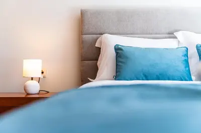 a bed with a blue pillow and a lamp on a table at GuestReady – Stay Near Historic Reis Magos Fort in Caniço