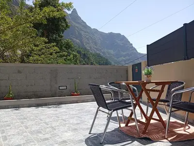a table and chairs on a patio with mountains in the background at Danny's Rural Suite T1 in Curral das Freiras