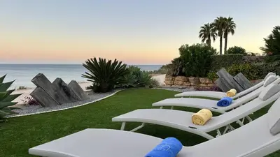 two white lounge chairs sitting on the grass near the beach at Luz by Check-in Portugal in Luz