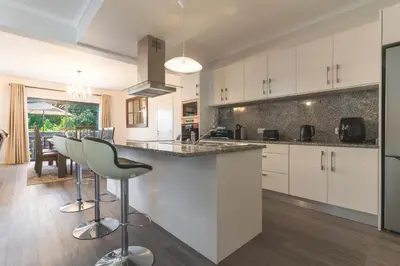 a kitchen with white cabinets and a bar with stools at Blue Outlook Garden by Atlantic Holiday in Água de Pena