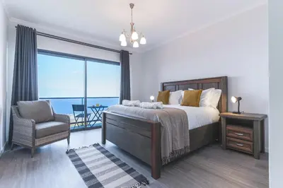 a bedroom with a bed and a chair and a large window at Blue Outlook Retreat by Atlantic Holiday in Água de Pena