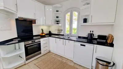 a kitchen with white cabinets and black counter tops at Casa Contente 3-bedroom villa with pool in Luz