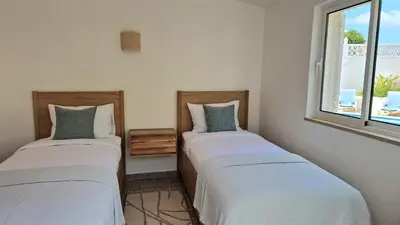 two beds in a room with a window at Casa Contente 3-bedroom villa with pool in Luz