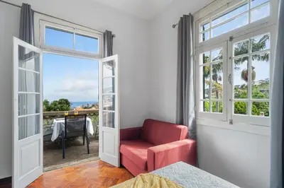 a bedroom with a red chair and a window at Akosuah's Villa in Funchal