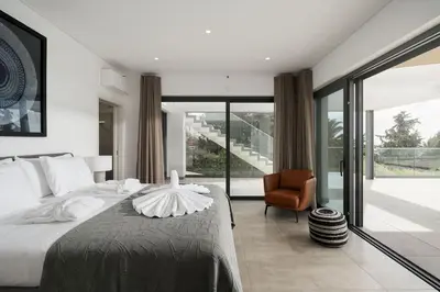 a bedroom with a large bed and a chair at Villa Vanguard by Destination Algarve in Montinhos da Luz