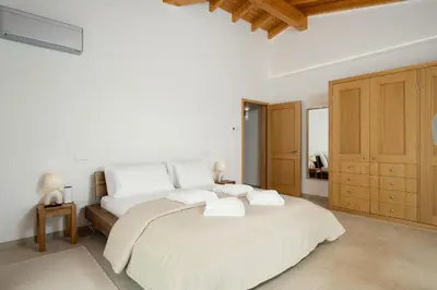 a white bedroom with a large bed and wooden cabinets at Villa Meridian by Destination Algarve in Mato Porcas