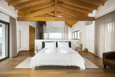 a bedroom with a large white bed with wooden ceilings at Villa Meridian by Destination Algarve in Mato Porcas