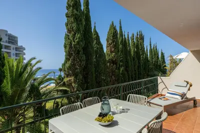 a balcony with a table and chairs and trees at Promenade II by An Island Apart in Funchal
