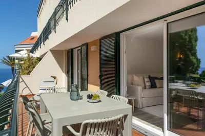 a white table and chairs on the balcony of a house at Promenade II by An Island Apart in Funchal