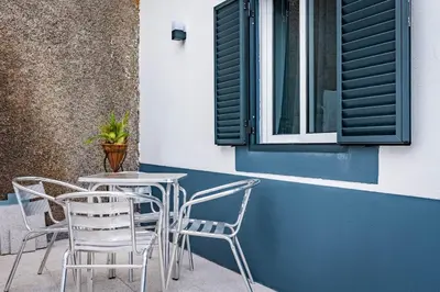a table and chairs on a patio with a window at Casa Ribeiro in Funchal