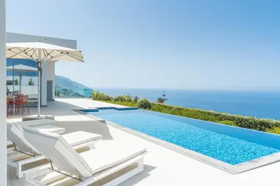 a villa with a infinity pool and chairs and an umbrella at Villa Alegria by Atlantic Holiday in Calheta
