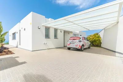 a white house with a car parked under awning at Villa Alegria by Atlantic Holiday in Calheta