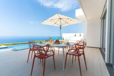 a table with chairs and an umbrella on a patio at Villa Alegria by Atlantic Holiday in Calheta