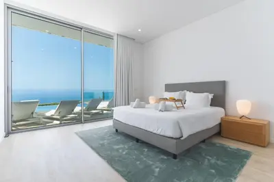 a white bedroom with a bed and a large window at Villa Alegria by Atlantic Holiday in Calheta